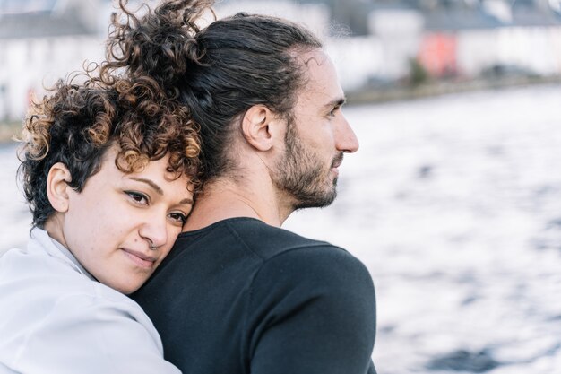 Girl hugging her partner  back with the  sea out of focus