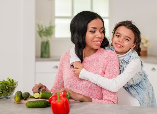Girl hugging mom while cooking