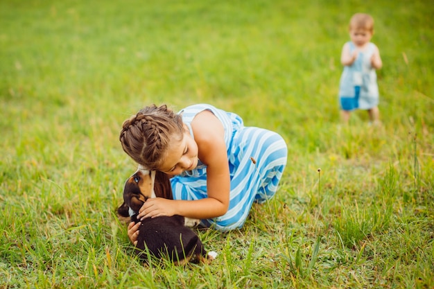 少女はフィールドに座って小さな子犬を抱擁