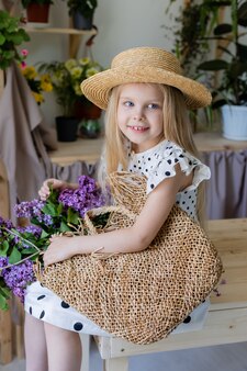 Девушка в платье в черный горошек и соломенной шляпе с букетом цветов сирени
