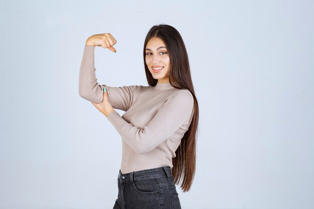 무료 사진 그녀의 주먹과 힘을 보여주는 회색 스웨터에 소녀.