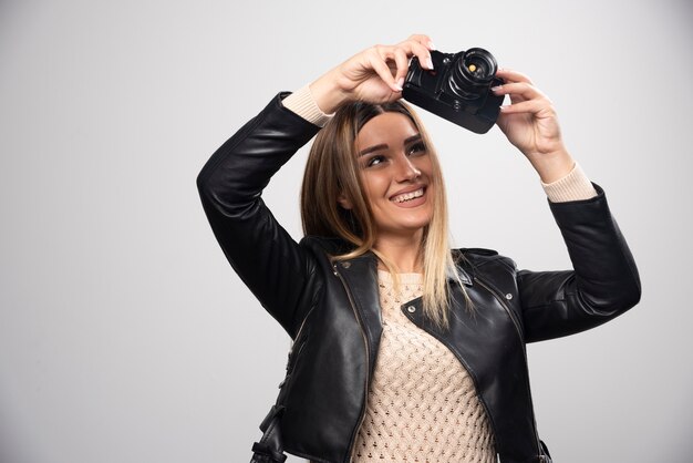 Бесплатное фото Девушка в кожаной куртке проверяет свою историю фотографий на камеру.