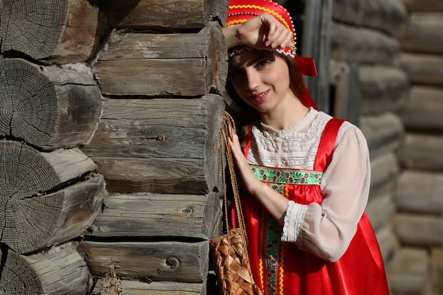 Девушка в традиционной одежде на деревянной стене