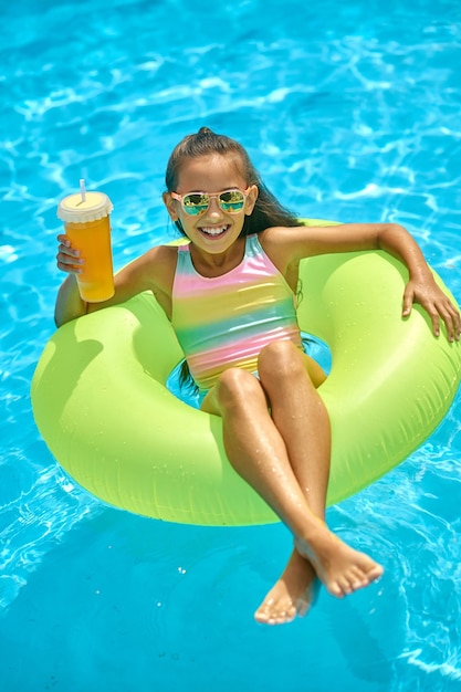 Girl on inflatable ring with drink looking at camera