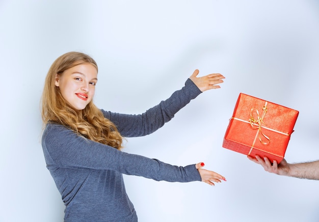 Foto gratuita alla ragazza viene offerta una confezione regalo rossa.