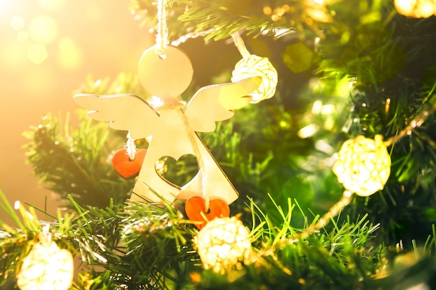 女の子​は​ライト​で​クリスマスツリー​を​飾っています​。​女性​の​手​に​ハート​の​おもちゃ​を​持つ​白い​天使​。​愛​と​休日​の​コンセプト​。​新年​の​気分​。​ヒュッゲスタイル​。​魔法​の​時間​。