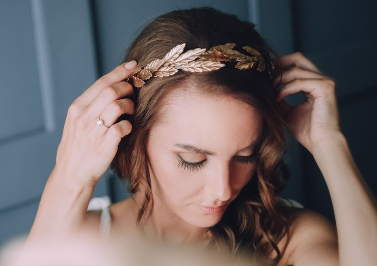 Free Photo girl is fixing on her head a golden hoop with laurel leaves