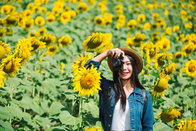 女の子はひまわり畑で写真を撮って幸せです。