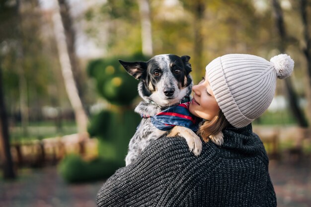 A girl is holding a mongrel dog in her arms. Caring for animals.