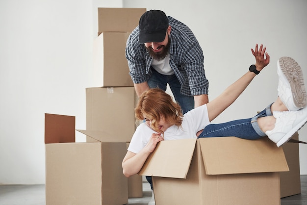 Girl is inside the box. Happy couple together in their new house. Conception of moving