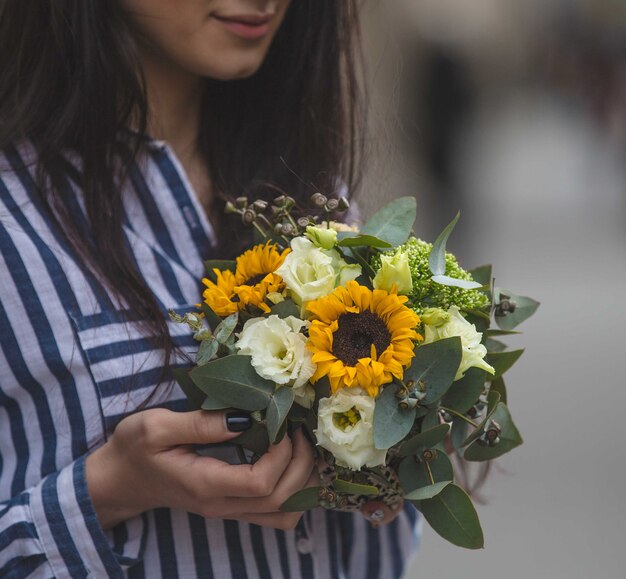 Girl is offered a bouquet of sunflowers and white roses