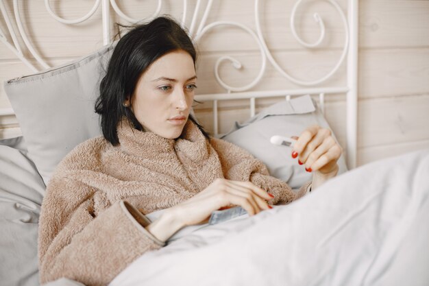 Girl is sick at home lying on the bed.