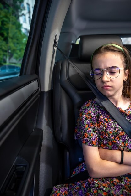 The girl is sitting in the car on the way to school