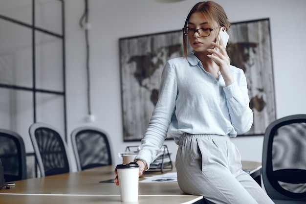 女の子がテーブルに座っています。電話で話している女性。コーヒーを飲むブルネット