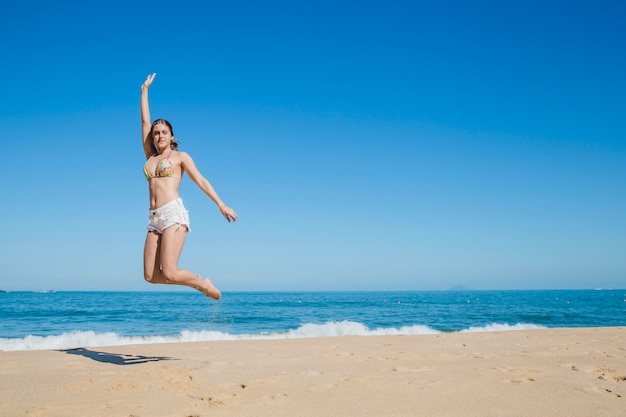 Девушка прыгает на пляже