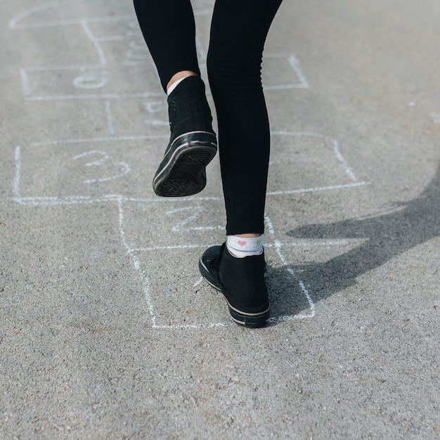 Girl jumping in chalk boxes drawn on asphalt