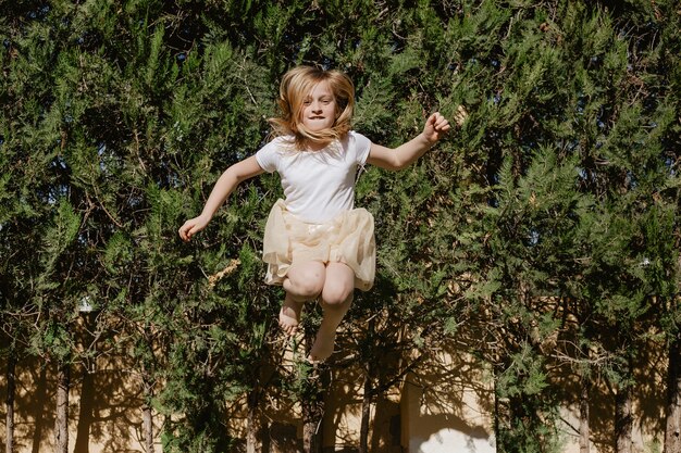 Девушка прыгает возле деревьев