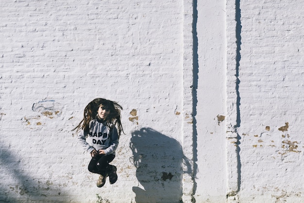 Girl jumping near white wall