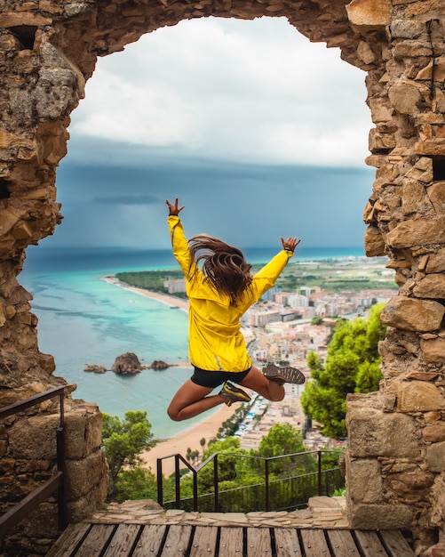 Girl jumping with excitement on a doorway with the sea