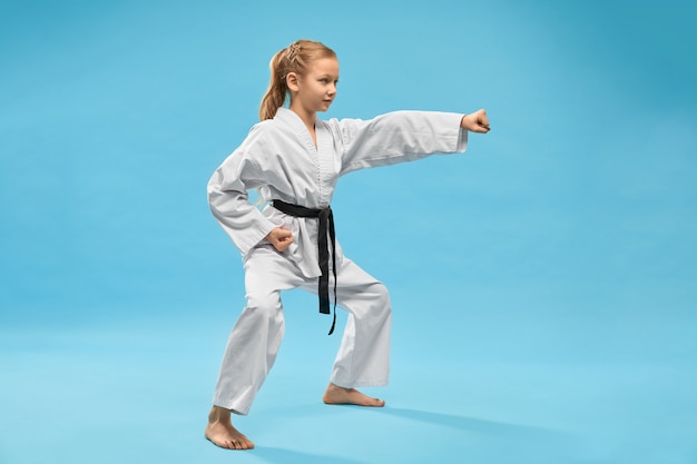 Girl in kimono standing in stance and punching with hand.