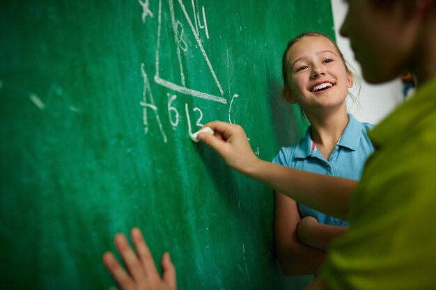 Girl laughing with her colleague writing on the blackboard