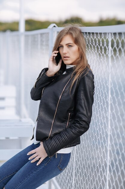 Girl leaning on a metal fence talking on the phone