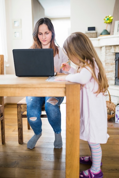 Ragazza che impara davanti a sua madre usando il portatile