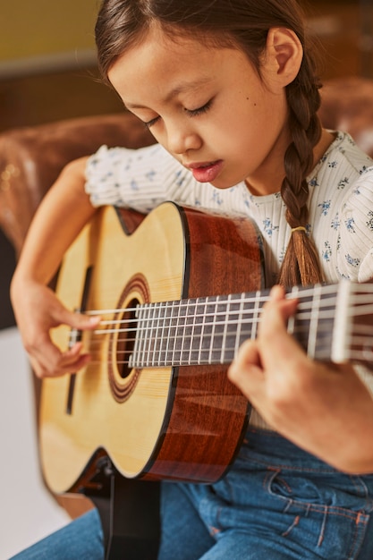 Девушка учится играть на гитаре дома