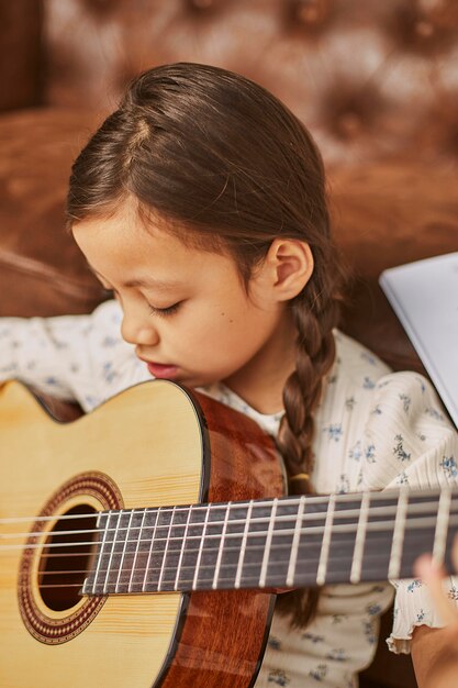 Девушка учится играть на гитаре дома
