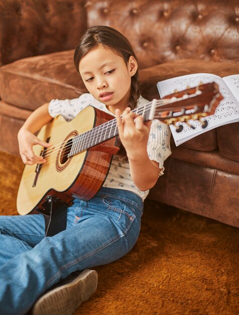 Girl learning how to play guitar at home