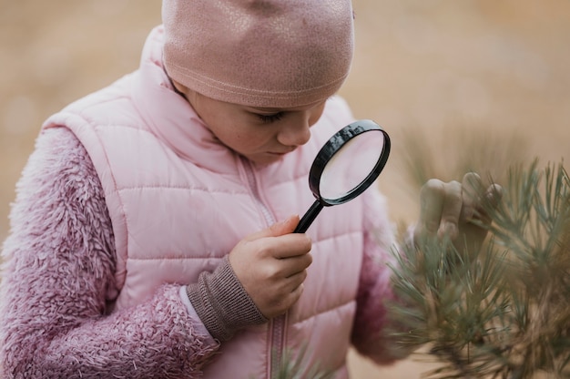 Girl learning science in the nature with a magnifier