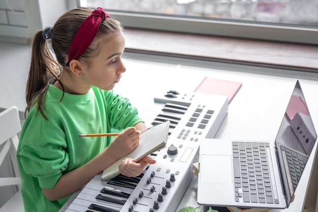 Free photo a girl learns to play the piano with a teacher online remote learning music