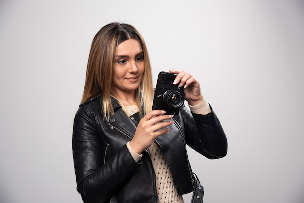 Foto gratuita ragazza in giacca di pelle che controlla la sua cronologia fotografica sulla fotocamera.