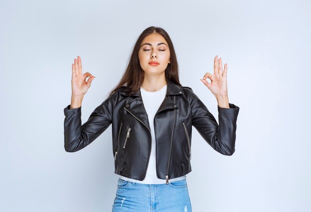 Girl in leather jacket showing enjoyment sign. 