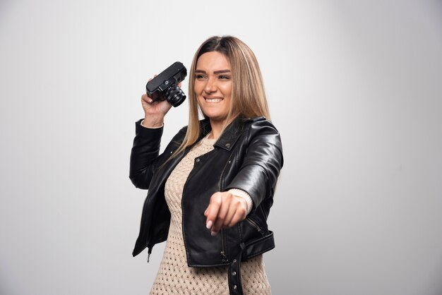 Girl in leather jacket taking her photos in funny and strange positions.