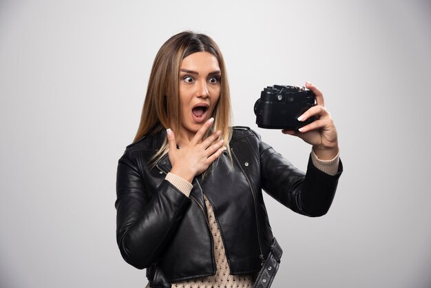 Girl in leather jacket taking her photos in funny and strange positions.