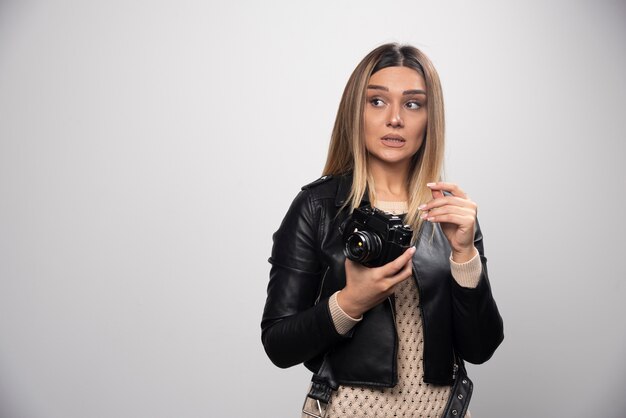Girl in leather jacket taking her photos in funny and strange positions.