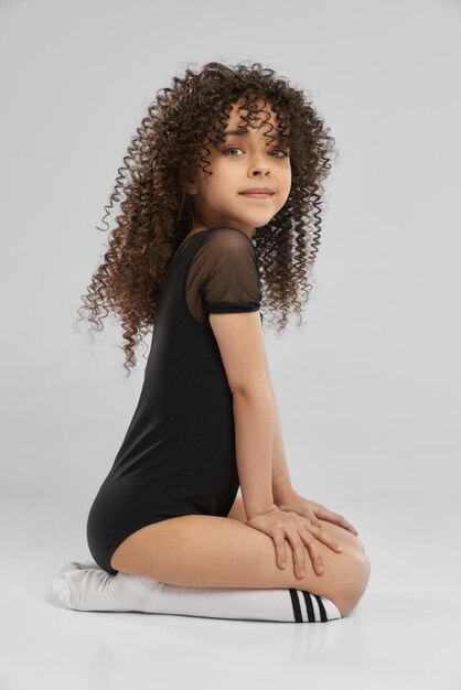 Girl in leotard sitting on studio floor