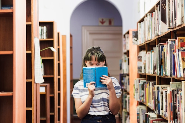 Free photo girl in library hiding face behind a book