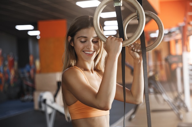 Girl likes holdingcrossfit gymnastics rings, smiling delighted.