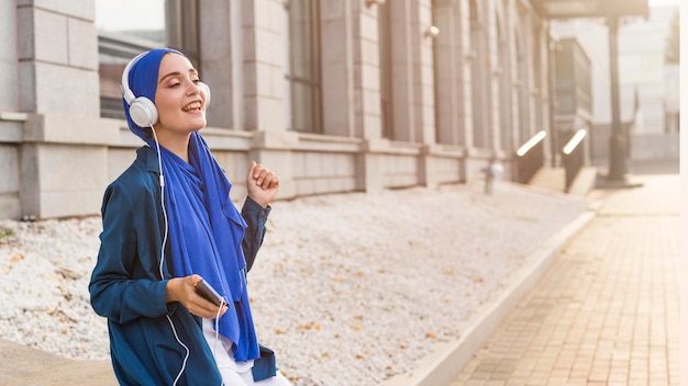 Girl listening to music through headphones outdoors with copy space