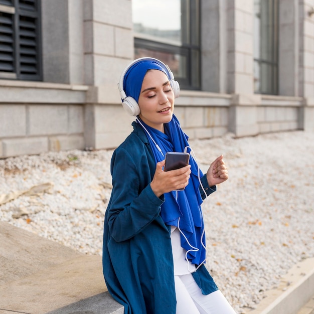 Free photo girl listening to music through headphones outdoors