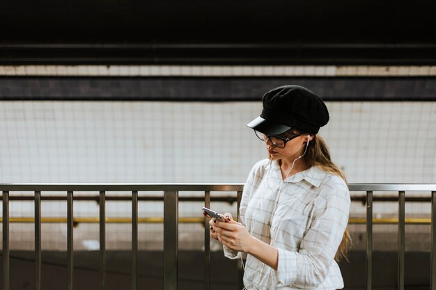 Girl listening to music while waiting for a train 