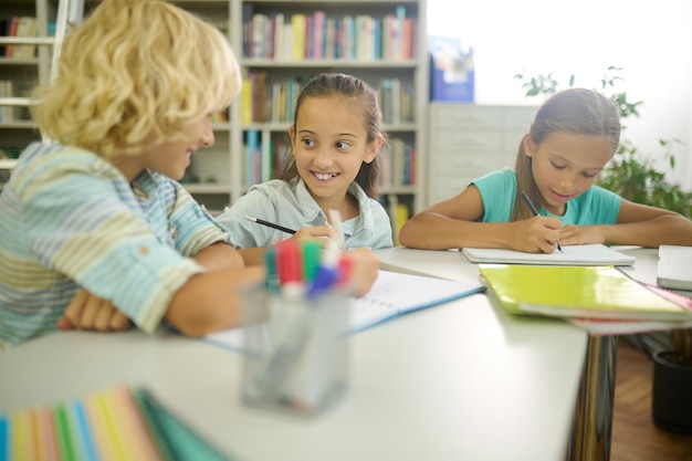 テーブルで書いている男の子を見ている女の子