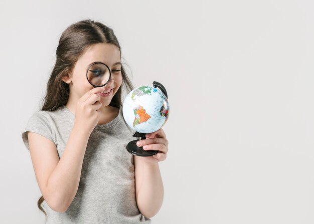 Girl looking at globe with loupe