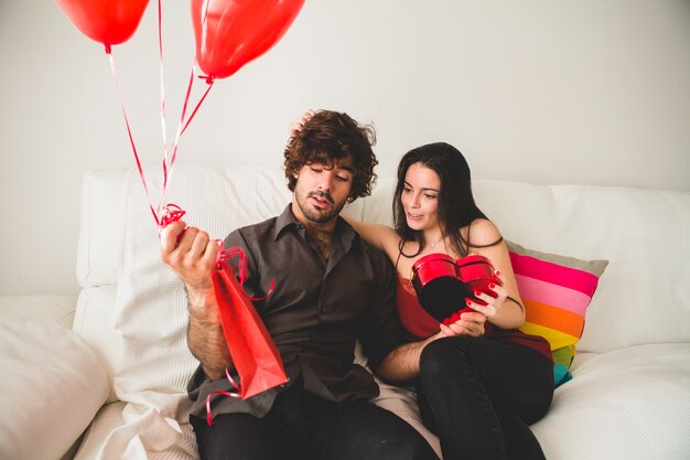 Girl looking at her boyfriend while opening a box of chocolates