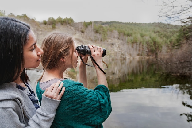 Girl looking at her friend while using binoculars