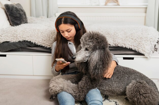 Ragazza che guarda il suo telefono mentre tiene in braccio anche il suo cane