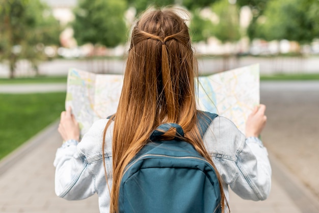 Free photo girl looking at a map from behind shot