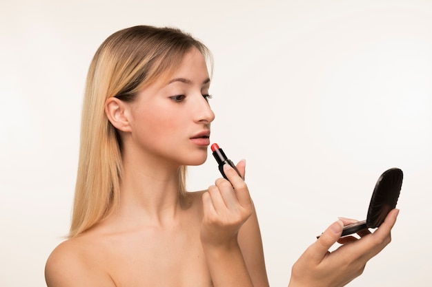 Girl looking in the mirror and putting on lipstick 